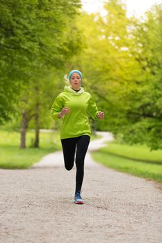 Sporty young female runner in city park.  Running woman. Female runner during outdoor workout in nature. Fitness model outdoors. Weight Loss. Healthy lifestyle. 