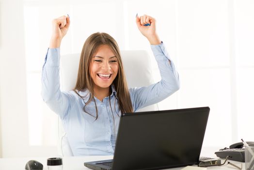Happy successful Businesswoman in the office with raised arms.