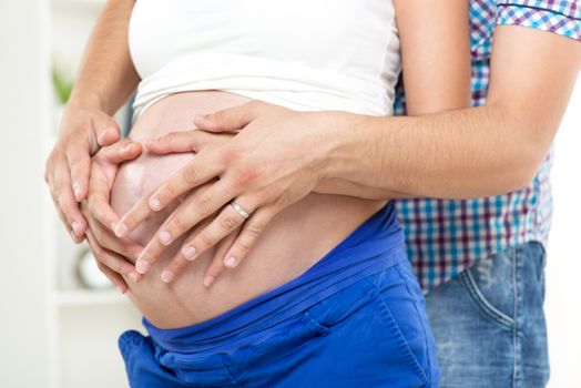 Male and female hands on pregnant woman's belly . 