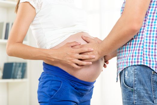 Male and female hands on pregnant woman's belly . 