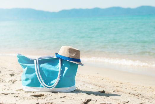Turquoise bag and hat on the beach.