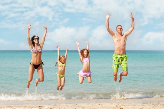 Family of four jumping at beach