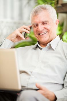 Happy senior businessman working at home on laptop