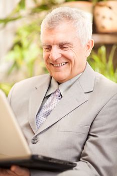 Happy senior businessman working at home on laptop