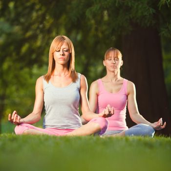 Two beautifu women meditating in the park