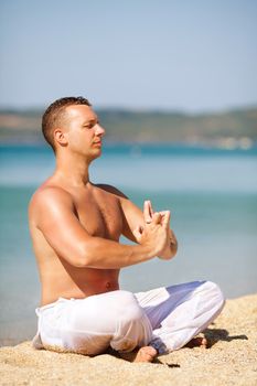 Young man meditating on the beach