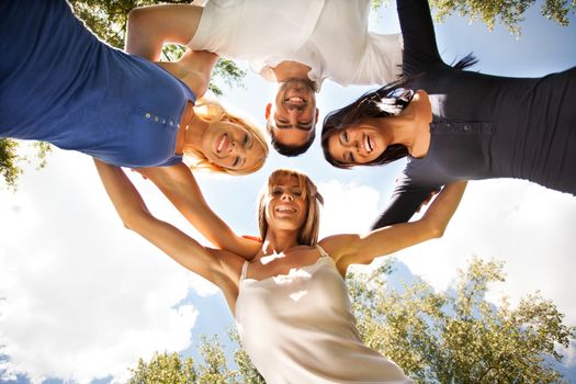 Happy friends standing in circle against the sky