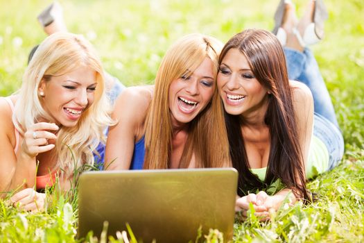 Beautiful girls with laptop at park surfing on the internet