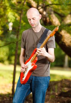 Young guitarist, playing guitar in beautiful nature environment