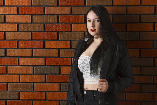 twenty something girl standing against a brick wall