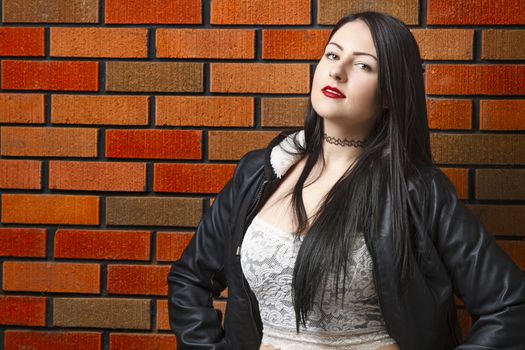 twenty something girl standing against a brick wall