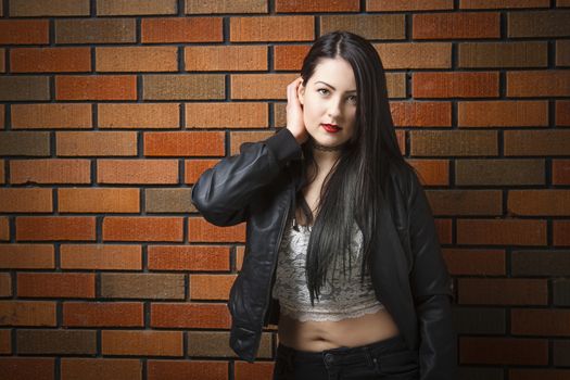 Young woman against a brick wall with rocker look