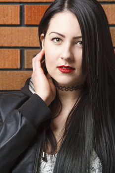 portait of a twenty something girl against a brick wall with red lipstick