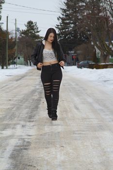 sexy twenty something girl with lace top adjusting her coat while walking in the middle of the street