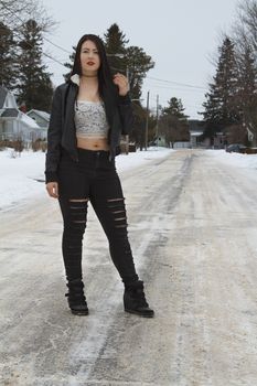 young model in rock style clothing standing in the street during winter