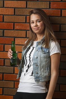 twenty something girl against a brick wall, with a beer