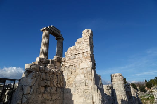 View of Didyma Ancient City in Aydın, Turkey, with granit columns and temple, on blue sky background.