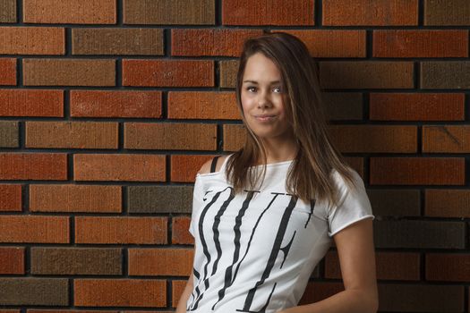 twenty something girl leaning against a brick wall