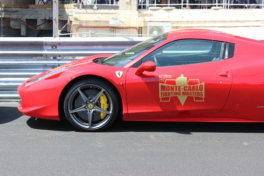 Monte-Carlo, Monaco - April 28, 2016: Red Ferrari 458 Italia Parked on the Street in Monaco. Guardrail of the Monaco Grand Prix in the Background