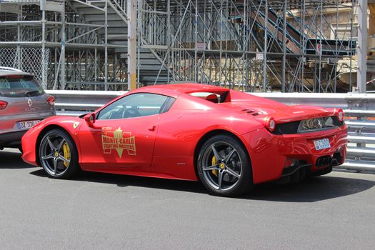 Monte-Carlo, Monaco - April 28, 2016: Red Ferrari 458 Italia Parked on the Street in Monaco. Guardrail of the Monaco Grand Prix in the Background