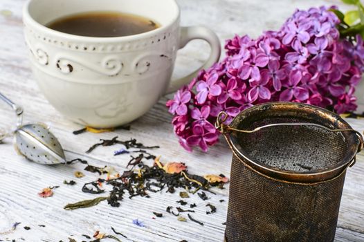 Custard flavored tea,spoon for welding and branch of blossoming lilac