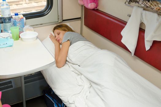 Girl sleeping in a train compartment on the lower second-class place car