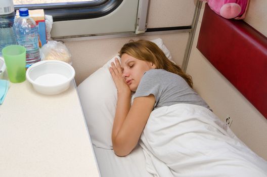 The girl on the train is fast asleep at a lower second-class place car coupe