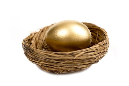 Close up shot of a golden egg laying in a nest and isolated on a white background