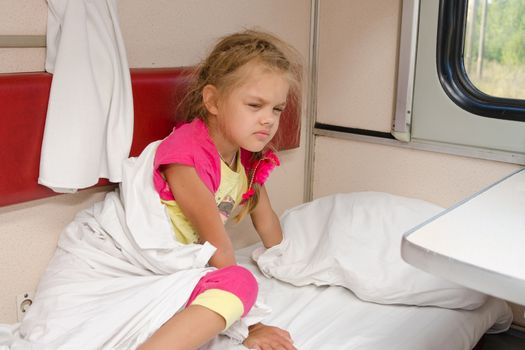 The girl on the train sleepily gets out of bed on the lower place in the second-class compartment wagon