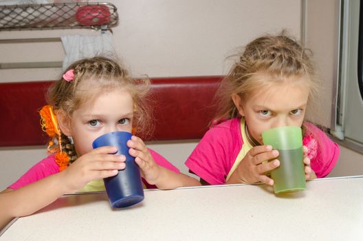 Two children drink tea in train at the table on the lower place in the second-class compartment wagon