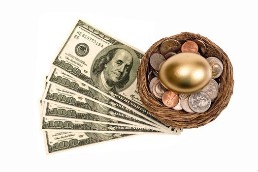 Golden nest egg resting on top of coins with currency or cash at the base.  Concept for saving money in your nest egg.