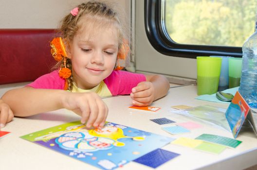 A small child in a train of fun playing at the table at the lower place in the second-class compartment wagon