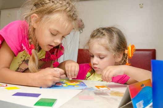 Two girls on the train sitting at the table on the lower second-class place car and enthusiasm make applique