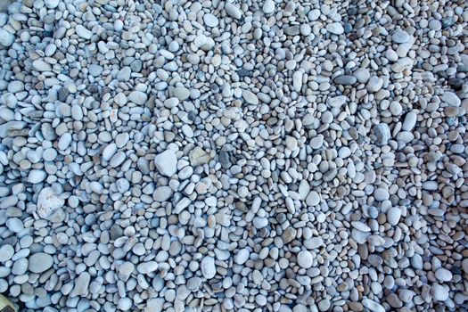 Naturally polished white rock pebbles background on beach