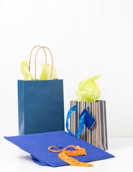 Blue graduation cap and two gift bags.  Ample copy space available.