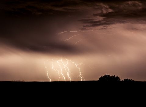 Multiple strieks of lightning at night against the ground.