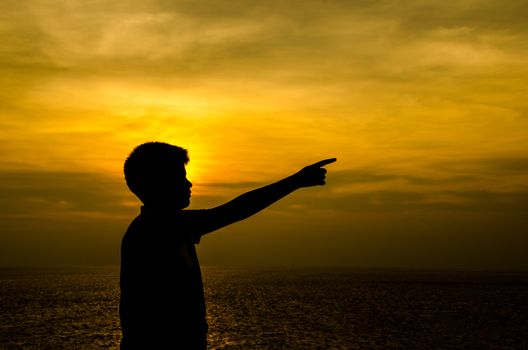 Silhouette of boy at sunset on ocean.
