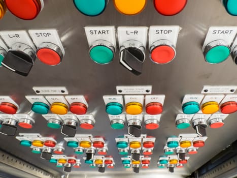 Industrial, electric switch panel with buttons in different colours. Dramatic perspective with shallow depth of field.