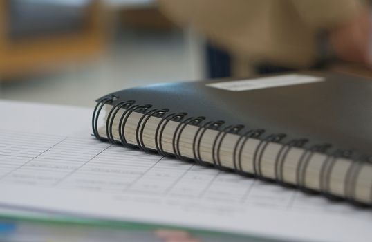 Black notebook and some report document placed in office room.