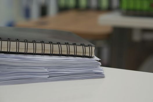 Black notebook and stack of data document on desk in office.