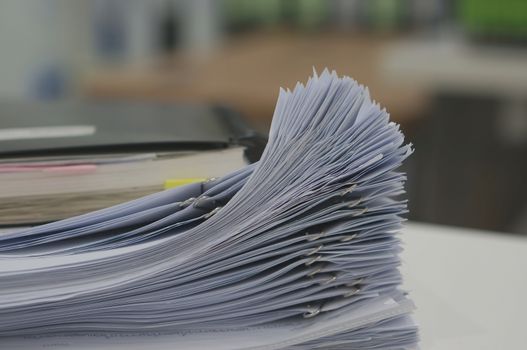 Stack of white document and notebook on desk in office.