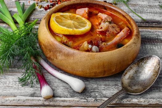 Traditional Solyanka with smoked meats in wooden plate