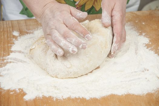 Women's hands preparing fresh yeast dough on wooden table