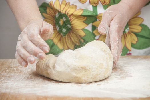 Women's hands preparing fresh yeast dough on wooden table