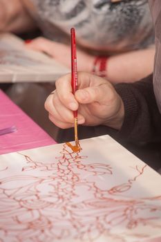 A woman hand with pencil is drawing picture with flowers