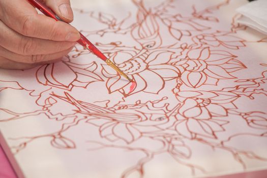 A woman hand with pencil is drawing picture with flowers