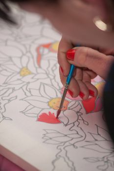 A woman hand with pencil is drawing picture with flowers