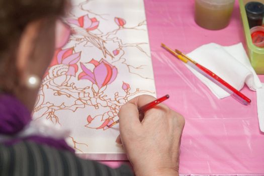 A woman hand with pencil is drawing picture with flowers