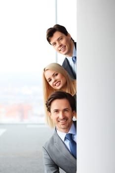 Happy business people looking out from corner in office