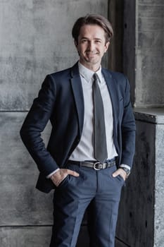 Portrait of smiling businessman in suit over concrete wall background